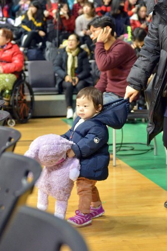 코트 안으로 들어가고 싶어하는 꼬마 관중을 아이 엄마가 잡고 있는 모습.